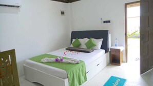 Un dormitorio ordenado con una cama, una mesita de noche, una silla y una puerta que da al exterior.