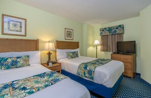 Une chambre d’hôtel avec deux lits, une télévision et un bureau avec une lampe.