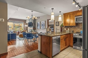 A modern kitchen with wooden cabinets, stainless steel appliances, and pendant lighting.