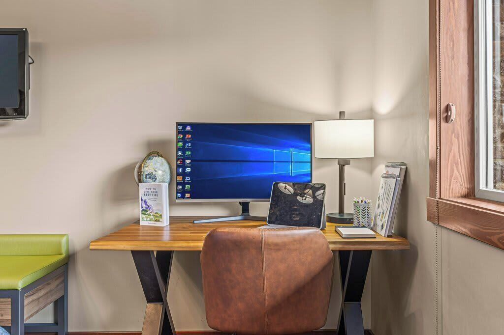 A workspace with a computer, desk lamp, and a chair.