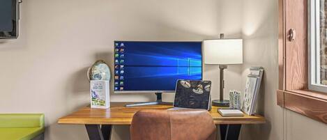 A workspace with a computer, desk lamp, and a chair.