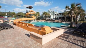 A pool area with a water slide, lounge chairs, and a poolside deck. - Seaside Serenity 10th Flr 3 Bdrm Newly Renovated (Myrtle Beach)