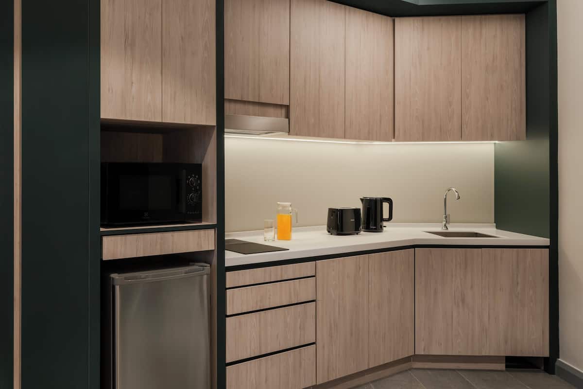 A modern kitchen with wooden cabinets, a stainless steel refrigerator, a microwave, a coffee maker, and a sink.