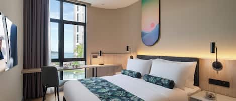 Habitación de hotel moderna con una cama grande, un escritorio y vistas a la ciudad.