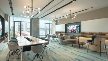 A modern conference room with a long table, chairs, and a large screen.