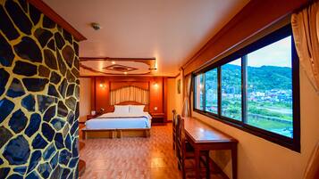 A bedroom with a large bed, a wooden table, and a view of a cityscape through a window.