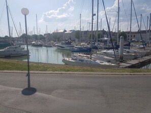 Un port de plaisance où sont amarrés de nombreux bateaux, un ciel dégagé et des bâtiments en arrière-plan.