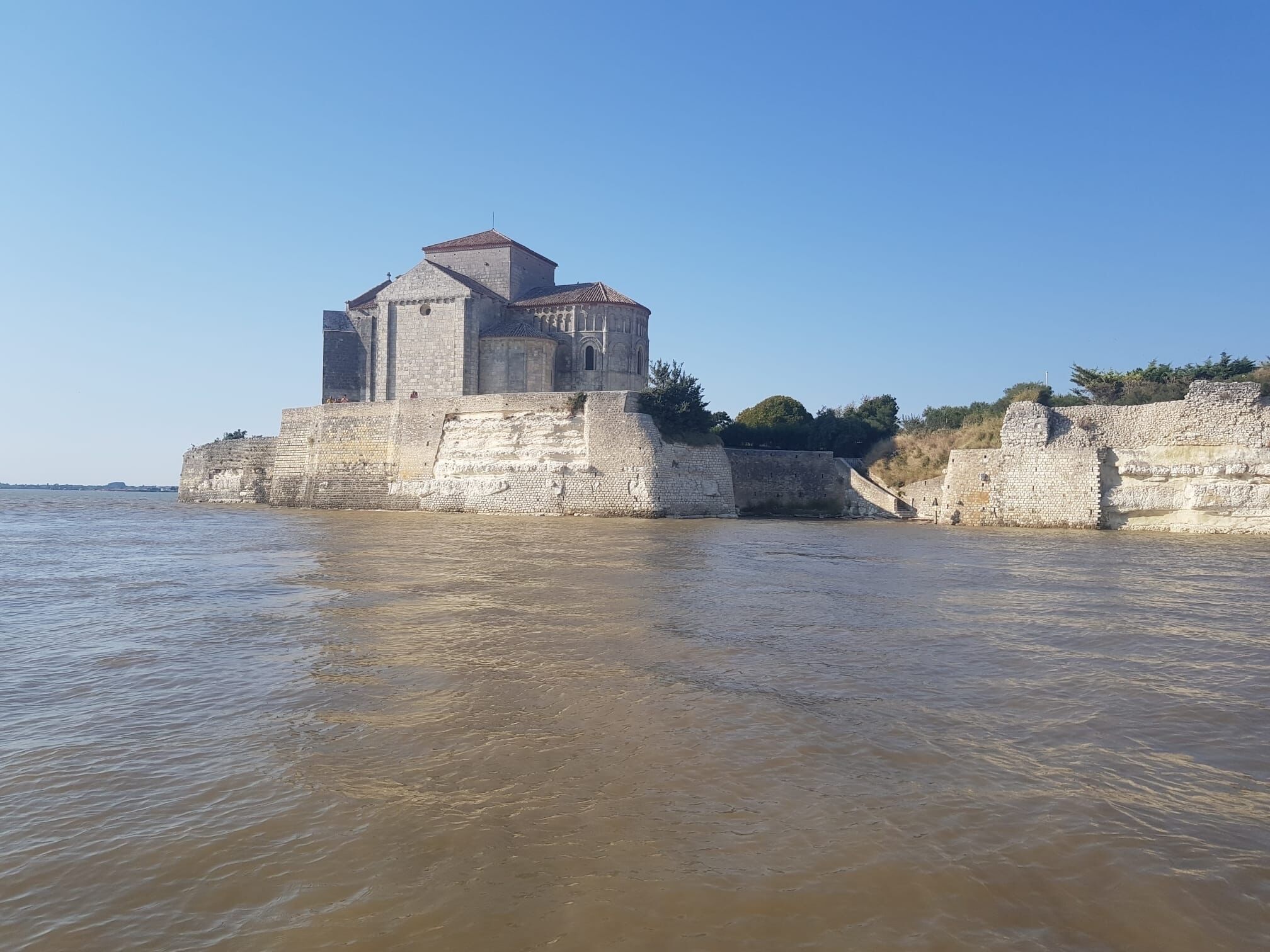 A historic stone building with a tower, situated by a river.