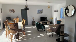 En moderne stue med spiseplads, møbleret med fletmøbler, et fladskærms-tv og et stort spejl.