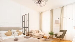 A modern bedroom with a large bed, a sofa, a chair, and a floor lamp. - City Apartment - 5 min to Metro (Vienna)