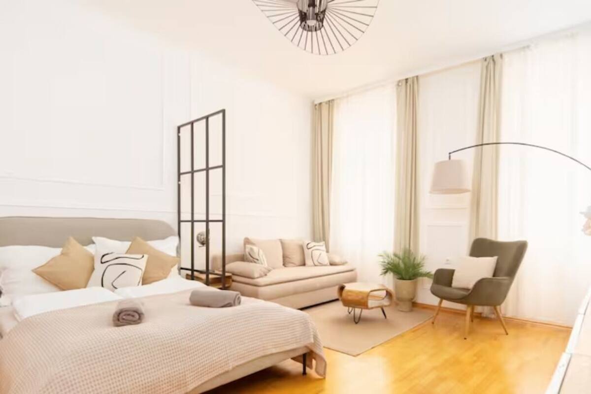 Une chambre moderne avec un grand lit, un canapé, un fauteuil et une lampe sur pied.