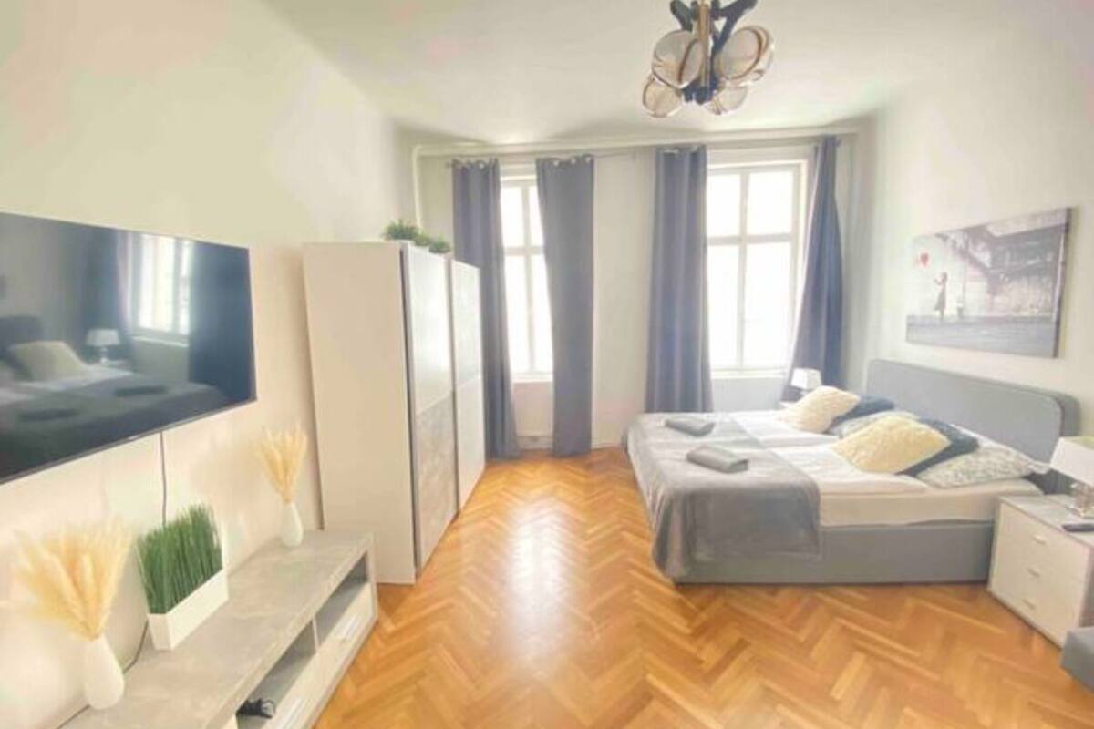 Une chambre à coucher moderne avec un grand lit, une télévision et un lustre.