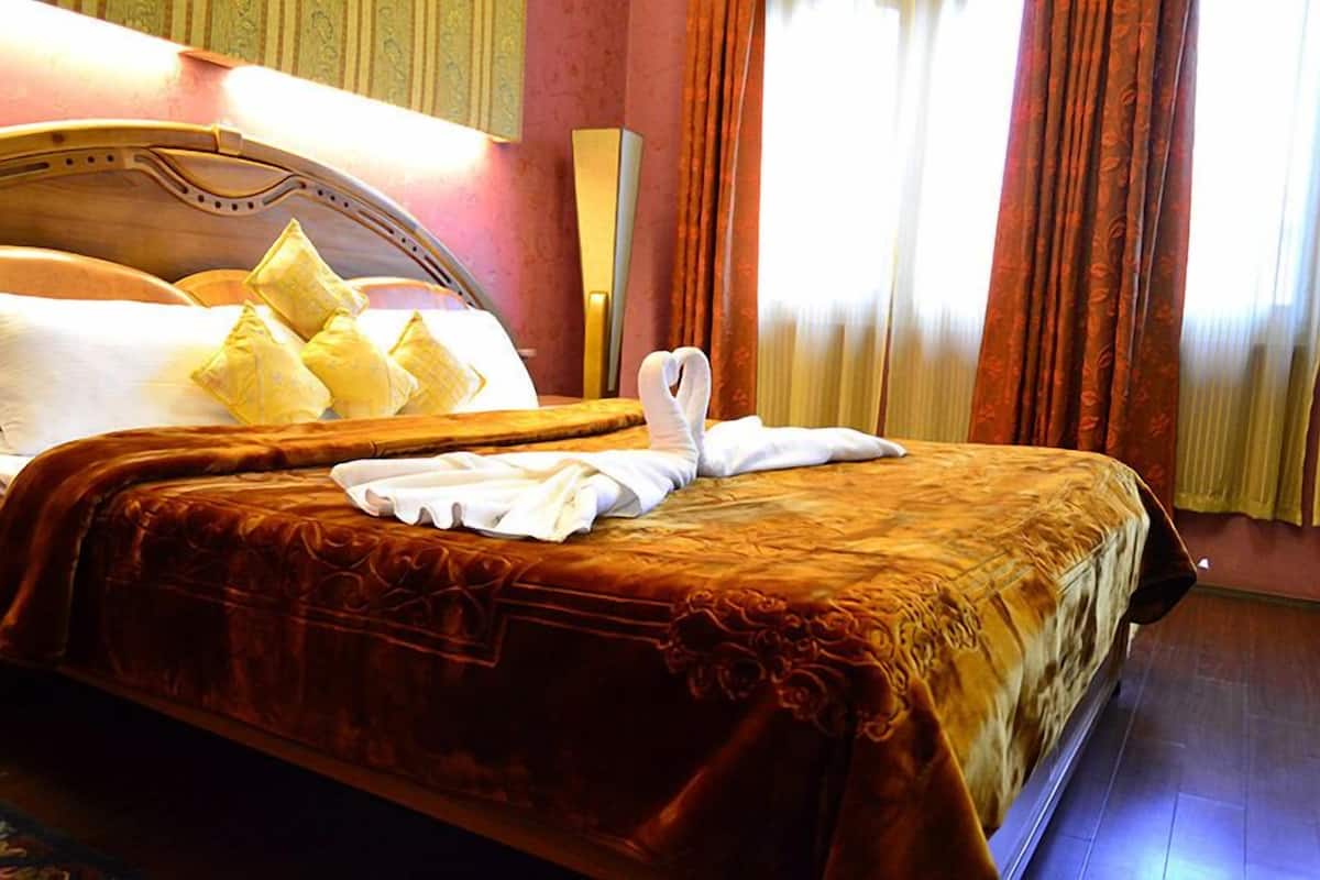 A hotel room with a large bed, a wooden headboard, and a decorative wall panel.