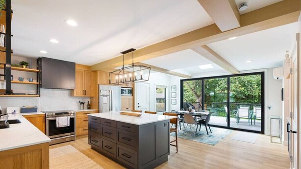 A modern kitchen with a central island, wooden cabinets, and a large window overlooking a garden. - Spacious & Bright ~ Water View (Seattle)
