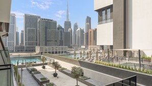 A rooftop terrace with a pool, seating areas, and views of the Dubai skyline including the Burj Khalifa. - WelHome - Contemporary 1BR in Binghatti Canal & Burj Views (Dubai)