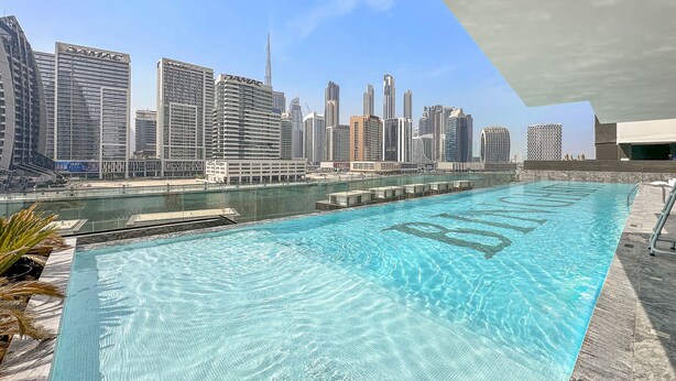 A swimming pool with a city skyline in the background. - WelHome - Contemporary 1BR in Binghatti Canal & Burj Views (Dubai)