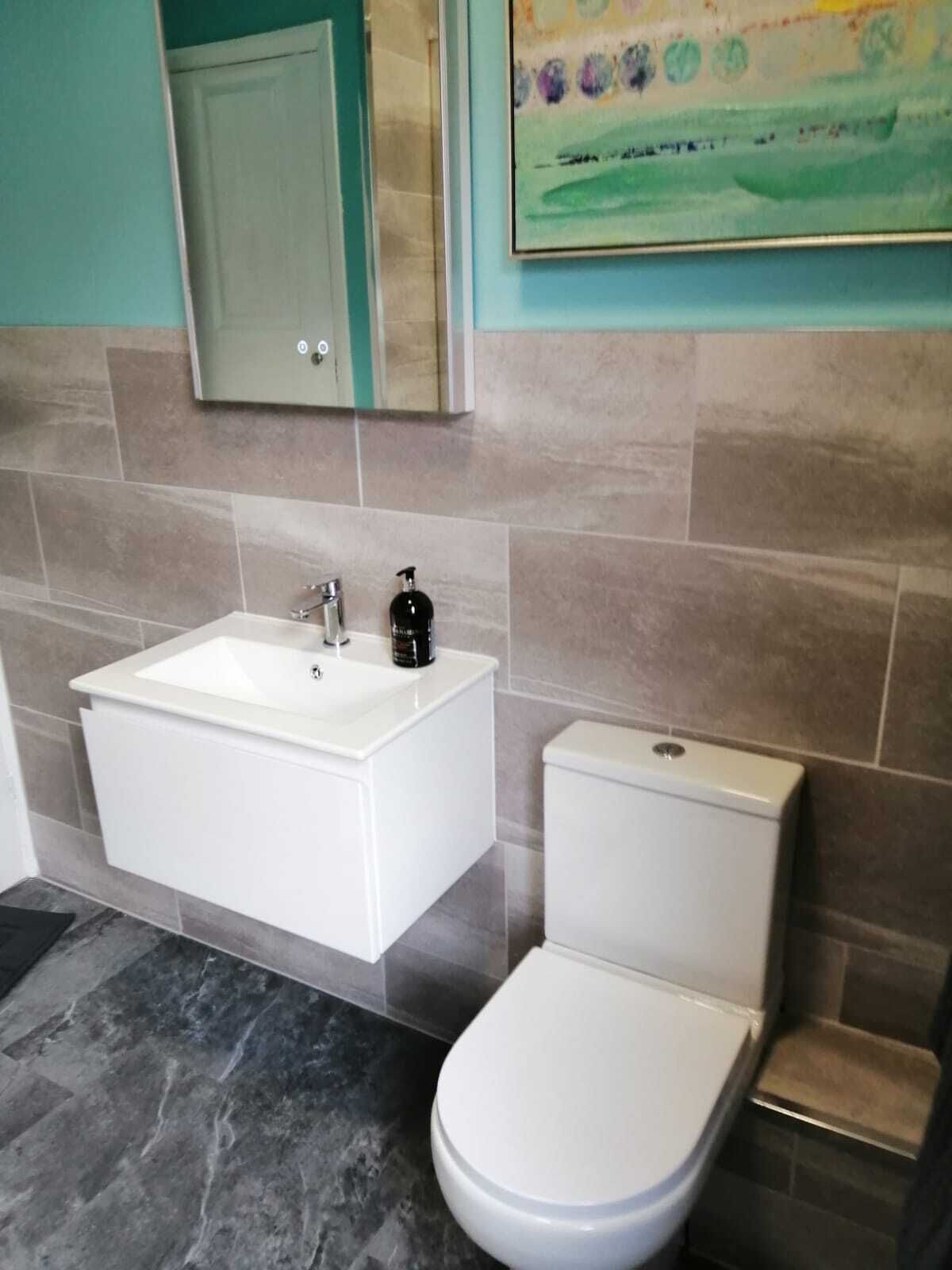 A bathroom with a white sink, a toilet, and a mirror above the sink.
