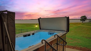 Un bain à remous avec vue sur un coucher de soleil se reflétant sur une étendue d’eau.