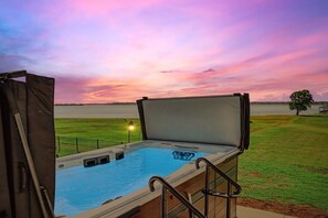 A hot tub with a view of a body of water and a sunset.