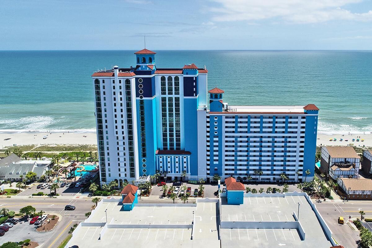 A large hotel with multiple floors and a beach view.