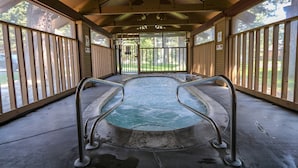 A covered hot tub area with metal railings and a concrete floor.