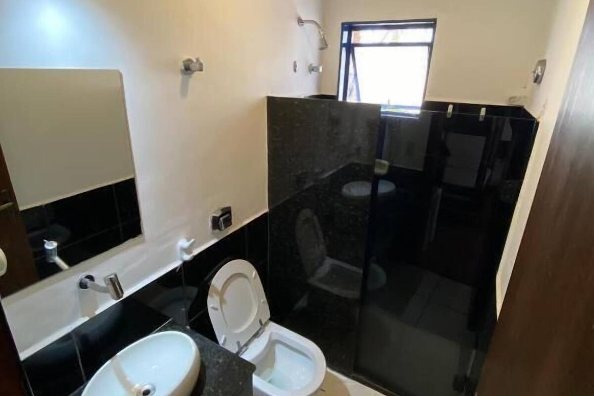 A bathroom with a white sink, a toilet, and a shower area.