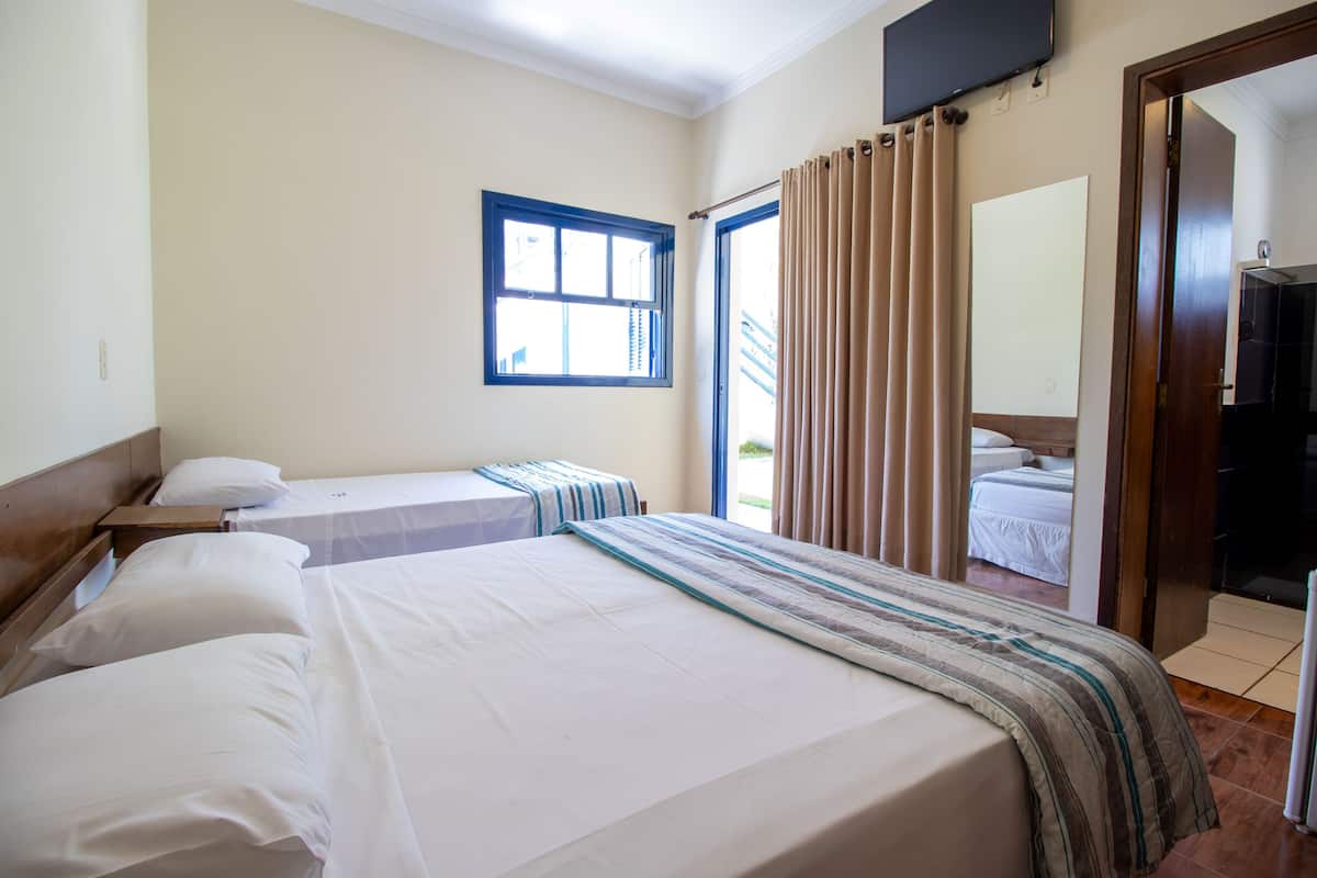 A hotel room with two beds, a window, a television, and a door leading to a balcony.