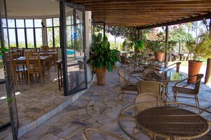 An outdoor patio area with stone flooring, wicker furniture, and potted plants.