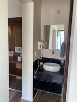 Un baño con un lavamanos blanco, un espejo, un perchero y una toalla colgada.