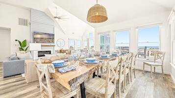 A spacious dining area with a long wooden table set for a meal, surrounded by wooden chairs.