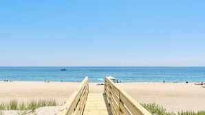 A wooden boardwalk leading to a sandy beach with a clear blue sky and calm sea. - Oceanfront Luxury Panoramic 6BR, Pool, Hot Tub, Game Room, Surf House OBX (Salvo)