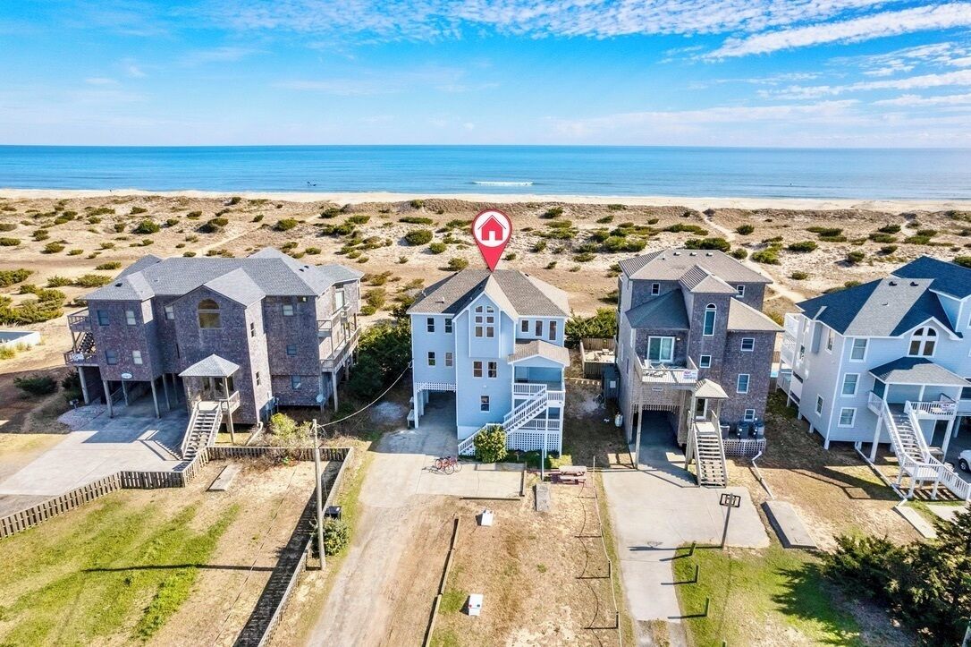 A beachfront residential area with multiple houses, including a central house with a prominent staircase and a red house marker icon.