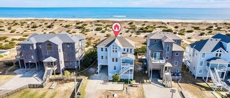 A beachfront residential area with multiple houses, including a central house with a prominent staircase and a red house marker icon.