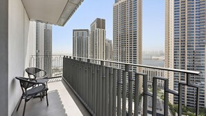A balcony with two chairs and a table, overlooking a cityscape with tall buildings.