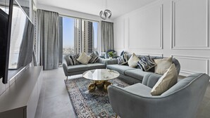 A modern living room with a grey sofa set, a round coffee table, and a large window offering a city view.