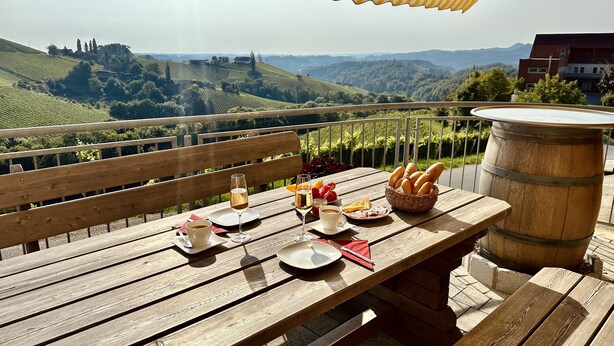 Mesa de madera al aire libre con vistas a colinas ondulantes y viñedos.