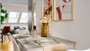 A dining area with a table set for four, a vase with flowers, and a framed picture of the Golden Gate Bridge. - Designer Apartments - Near Reumannplatz (Vienna)