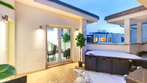 A rooftop terrace with a glass door leading to a balcony, a potted plant, and a snow-covered floor. - Designer Apartments - Near Reumannplatz (Vienna)