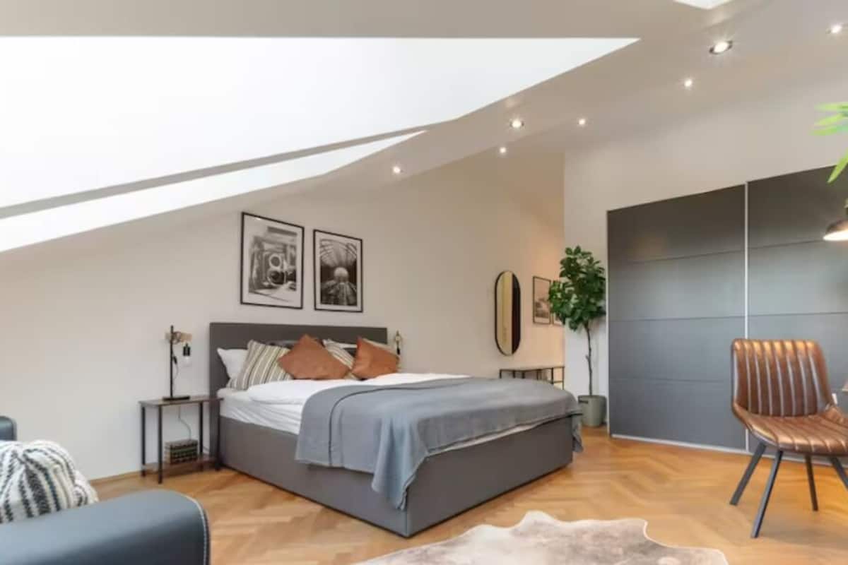 A modern bedroom with a bed, bedside tables, a desk, and a chair.