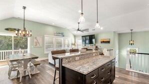 A spacious kitchen with a large island, wooden flooring, and pendant lighting. - Irie: New Build | Private Pool | Hot Tub (Corolla)
