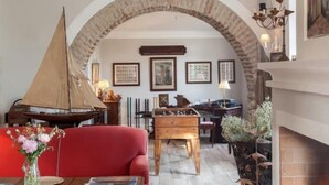 A cozy living room with a red sofa, a wooden coffee table, a fireplace, and a large arched doorway leading to another room.