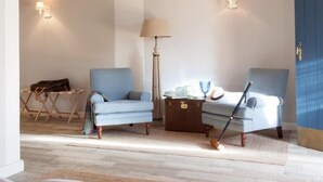 A modern living room with two blue armchairs, a floor lamp, and a small table.
