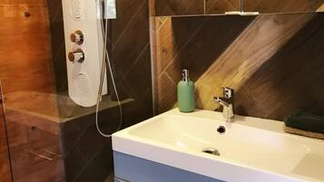 Une salle de bain moderne avec une douche, un lavabo et un miroir.