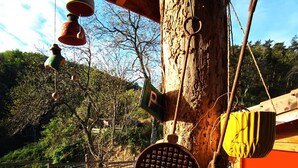 A rustic outdoor area with a tree, a metal pot, and a wooden structure. - Farm cottage with view of the Vercors 4 pers (Saint-Péray)