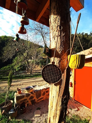 A rustic outdoor area with a tree, a stone wall, and a wooden structure with a 'P' sign.