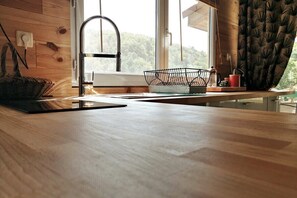 A kitchen with a wooden countertop, a sink, and a window with curtains.