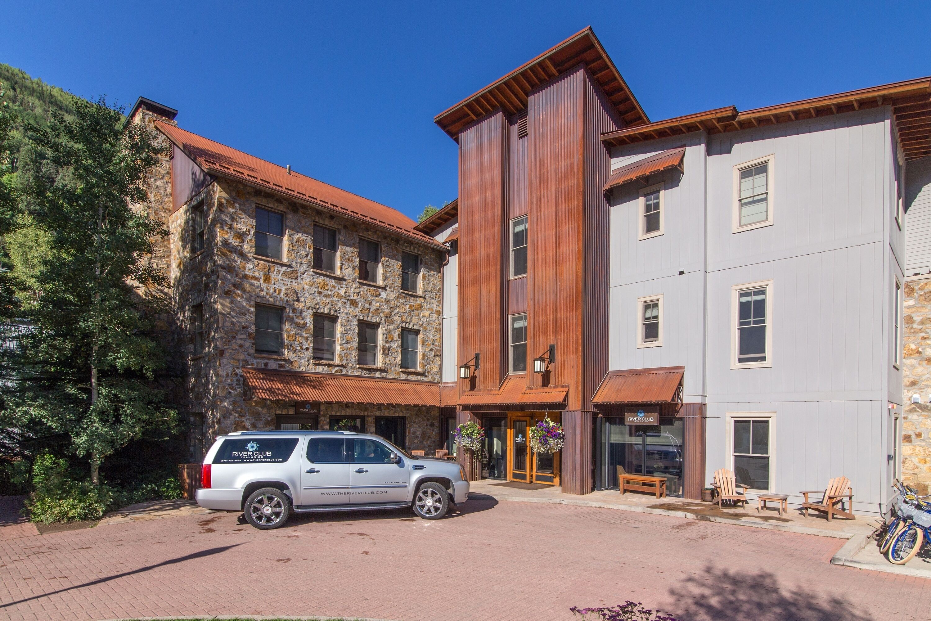 Un hôtel à la façade en pierre, à l’extérieur en bois, avec une voiture garée devant.