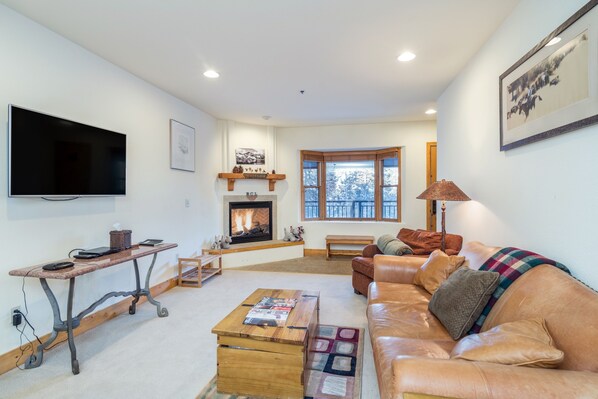 A living room with a fireplace, leather sofa, and a flat-screen TV. - Bear Creek Lodge 109 2 Bedroom Condo by Alpine Lodging Telluride (Telluride)