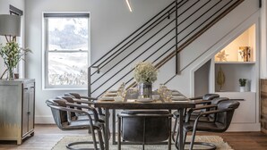 A dining area with a large window, a staircase, and a table set for six. - Bear Creek Lodge 412 4 Bedroom Condo by Alpine Lodging Telluride (Telluride)