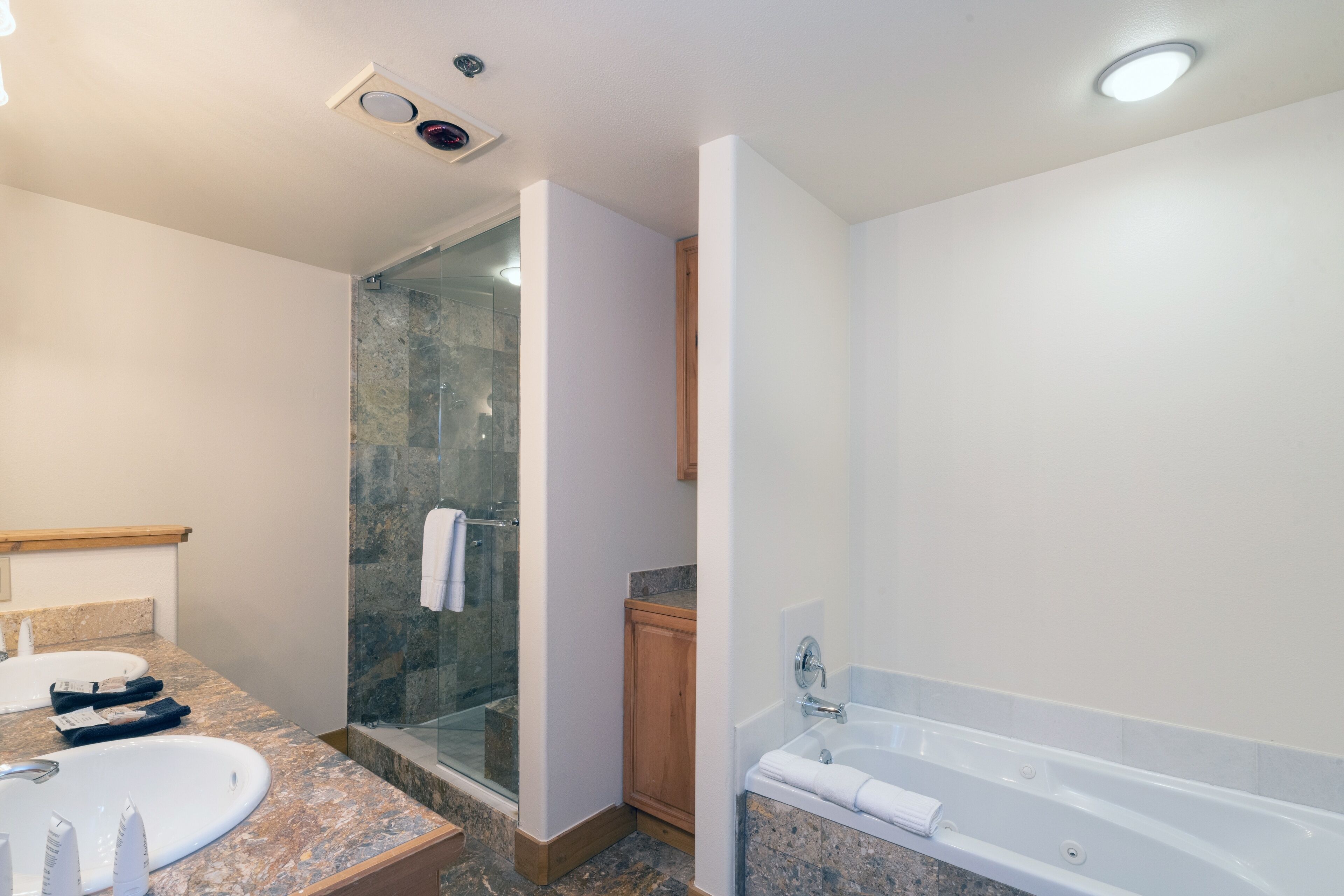 Une salle de bain moderne dotée d’une douche à parois de verre, d’une grande baignoire et de deux lavabos.